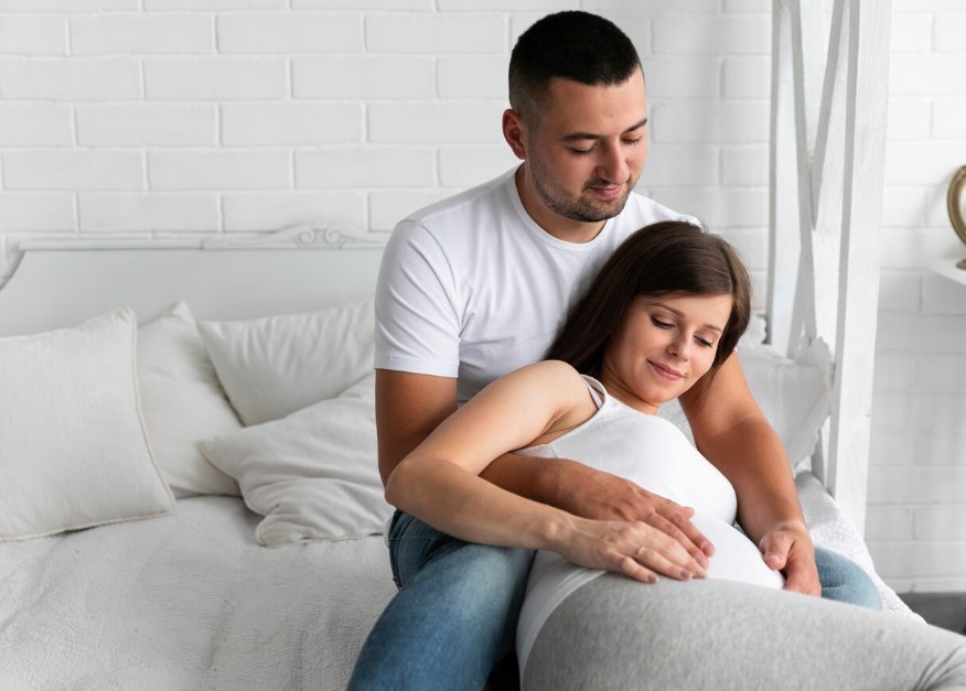 pareja embarazada recostada en una cama